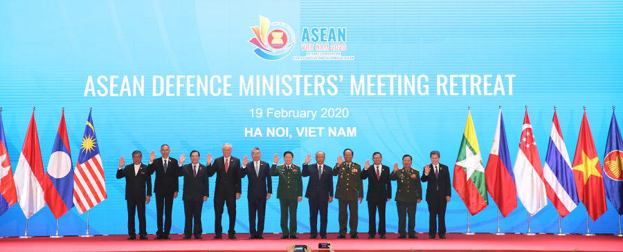ASEAN Defence Ministers' Meeting with flags and attendees raising their right hands.
